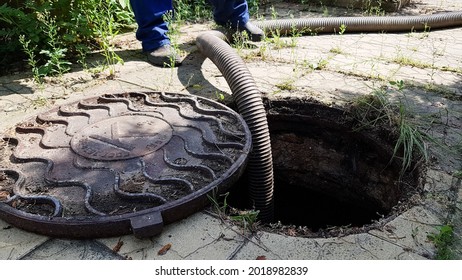 The Worker Opened The Sewer Hatch And Inserted A Hose For Cleaning The Septic Tank. Maintenance Of Communications In A Private House. Dirty Work