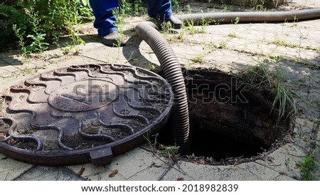 the worker opened the sewer hatch and inserted a hose for cleaning the septic tank. maintenance of communications in a private house. dirty work