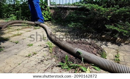 the worker opened the sewer hatch and inserted a hose for cleaning the septic tank. maintenance of communications in a private house. dirty work. summer