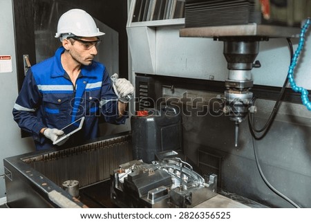 Worker Operates EDM Machine inspecting Metal injection mold production in Thermoplastic Factory.