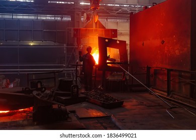 Worker operates metal casting process in metallurgical plant