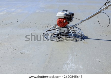 Worker operates trowel machine to level freshly poured concrete in open construction area, ensuring flawless finish.