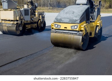 Worker operating vibratory road roller compactor process machine laying new asphalt on construction site - Powered by Shutterstock