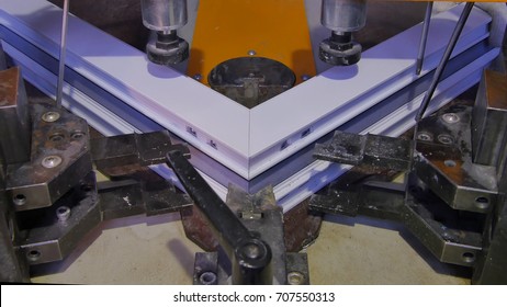 Worker Operating Welding Machine in Factory. Pvc Window Welding Machine. Aluminium Window Frame Press Machine. Worker produces a window from plastic. Industrial press with danger sign close up.
