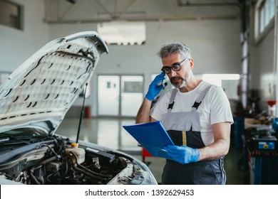 Worker Ordering Car Parts Over Cellphone In Car Service