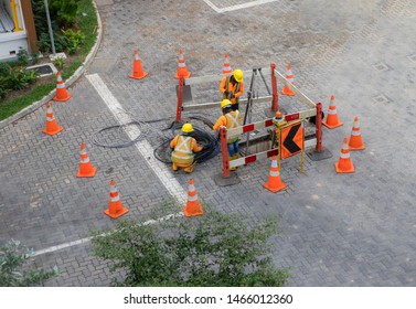 Worker over the open sewer hatch on street,Electricity and communication repair underground utilities cable laying 
a backgroung