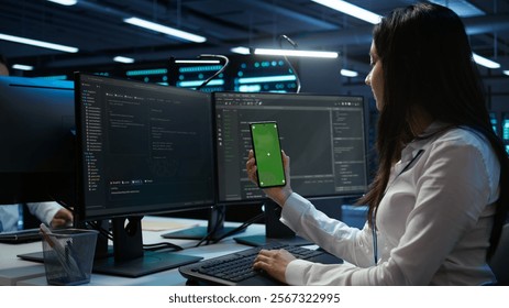 Worker overseeing data center using green screen mobile phone, ensuring system can handle networking tasks. IT expert in server room tracking network traffic with empty copy space smartphone, camera B
