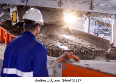 Worker overseeing the sorting and processing of refuse-derived fuel (RDF) in an industrial facility, highlighting the recycling and waste management process in the renewable energy sector. - Powered by Shutterstock