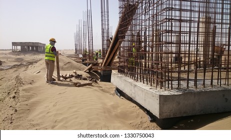 A Worker Oversees The Construction Of A Building In The Desert