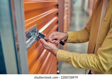 Worker Padlocking The Door Of The Storage Unit