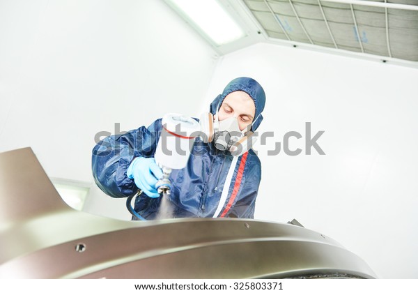worker  painting auto car bumper in a paint chamber\
during repair work