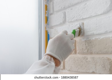 Worker Is Painting A Brick Wall With A Brush.