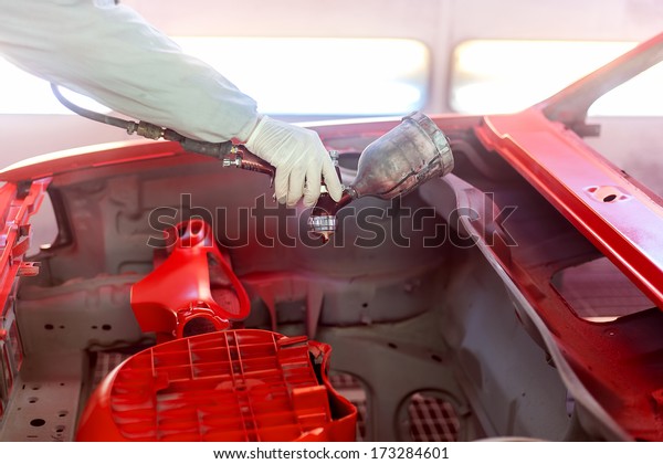 worker painting a car element, the hood with
special paint and tools