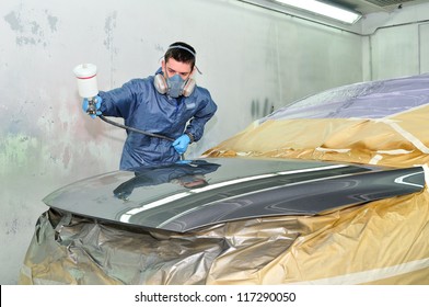 Worker Painting A Car In Paint Booth.