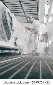 Worker Painting Car In A Paint Booth, Low Angle Image.