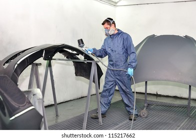 Worker Painting Car Parts In A Paint Booth.