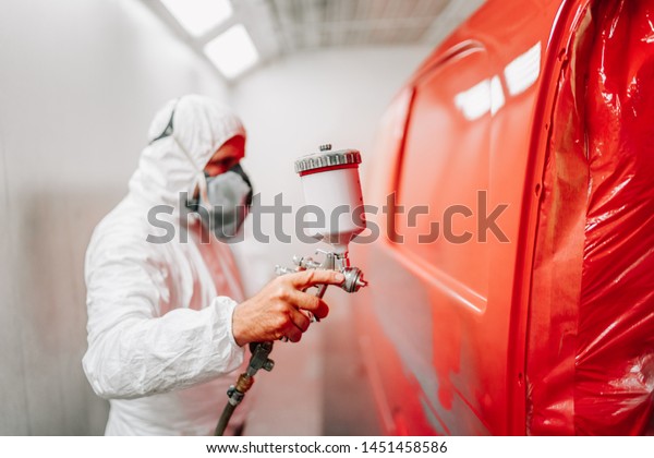worker painting a\
car using a paint spray\
gun