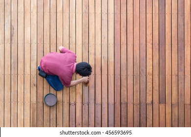 A Worker Painting Exterior Wooden Pool Deck, Top View