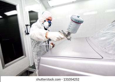 worker painting a grey car in a special booth