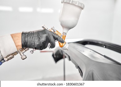 Worker painting parts of the car in special painting chamber, wearing costume and protective gear. Car service station. - Powered by Shutterstock