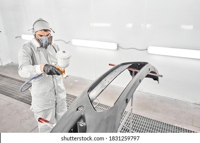 Worker painting parts of the car in special painting chamber, wearing costume and protective gear. Car service station. - Powered by Shutterstock