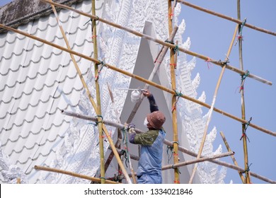 Worker Painting Roof In White Colors With Paint Spray Gun.