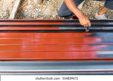 A Worker Painting Rustproof On Steel Poles For Construction.