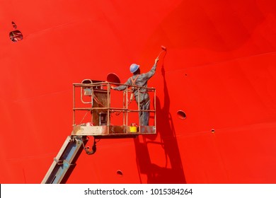 Worker Painting Ship Hull On Sherry Picker Using Paint Roller