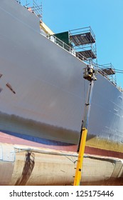 Worker Painting Ship Hull Using Airbrush.