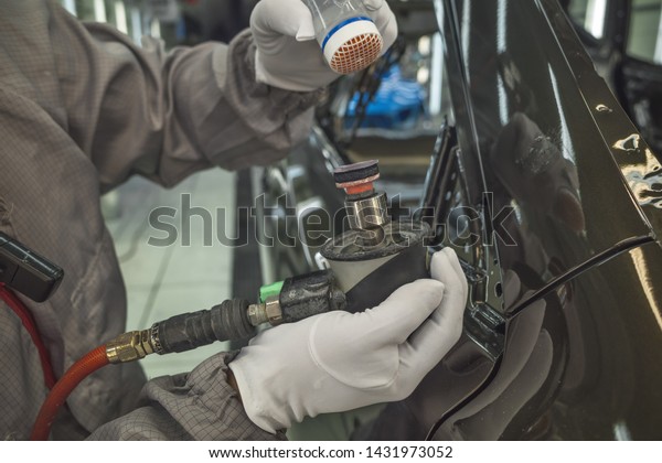 A worker in the painting shop of a car body,\
sanding painted items