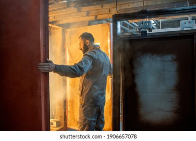 Worker Of The Painting Shop Checking Metal Products Into The Oven For Baking Powder Paint. Powder Coating Process At The Manufacturing. High Quality Photo