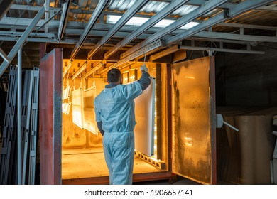 Worker of the painting shop pushing metal products into the oven for baking powder paint. Powder coating process at the manufacturing. High quality photo