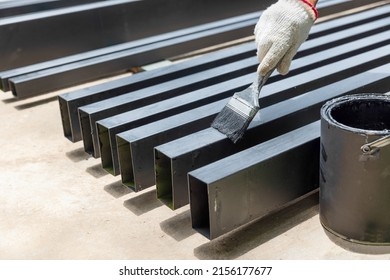 Worker Painting Steel Post In Construction Site.