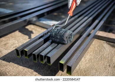 Worker Painting Steel Post In Construction Site.