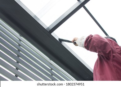 Worker Painting Steel Roof Structure, Under The Roof Top.