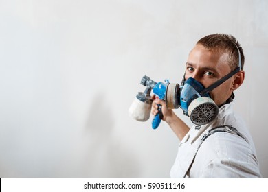 Worker Painting Wall With Spray Gun In White Color.