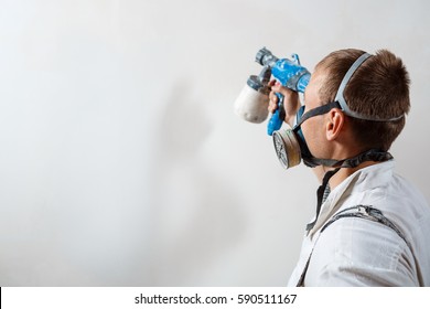 Worker Painting Wall With Spray Gun In White Color.