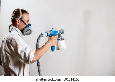 Worker Painting Wall With Spray Gun In White Color.