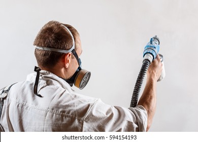 Worker Painting Wall With Spray Gun In White Color.