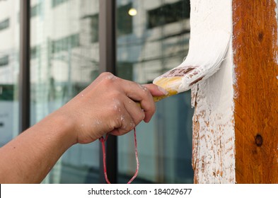 Worker painting wood with paint brush.
