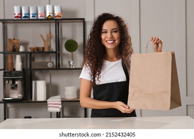 Worker with paper bag at counter in cafe, space for text