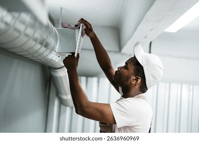 Worker performs maintenance on ventilation system in commercial building during daylight hours