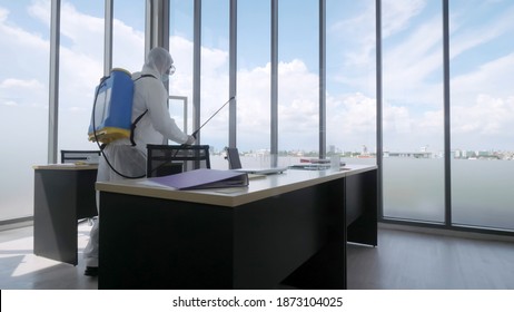 Worker In Personal Protective Equipment (ppe) Suit Cleaning In Building With Spray Disinfectant Water To Remove Covid 19.