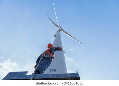 worker in Personal Protective Equipment work with wind turbine farm.  people in Safety Harness work on wind mill.