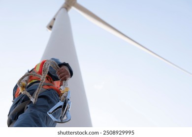 worker in Personal Protective Equipment work with wind turbine farm.  people in Safety Harness work on wind mill. - Powered by Shutterstock