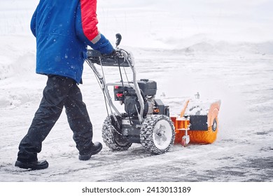 Worker with petrol snow sweeper clean area from snow during blizzard. Worker sweep snow from sidewalk. Man with snowthrower clear snow and ice in winter season