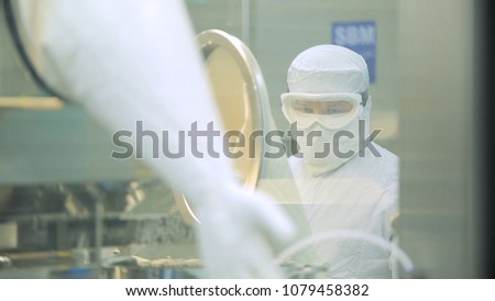Worker At Pharmaceutical Factory. Lab technician working inside a pharmaceutical factory. Pharmaceutical manufacturing. Operating control panel of the pharmaceutical machine