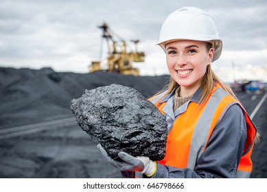 worker with piece of coal in her hand at an open pit
