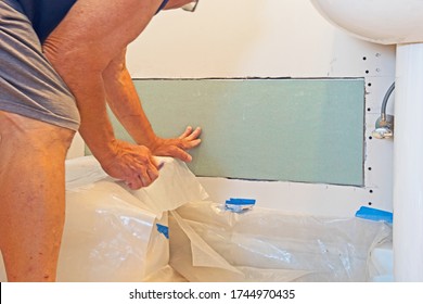 A Worker Places A Drywall Patch Over A Hole In Order To Ensure That It Is The Correct Size.