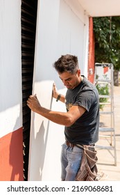 Worker Placing Drywall Sheets On Metal Structure